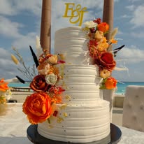 Pastel de boda con flores en tonos cálidos frente al mar